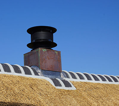 Detail rieten dak met nieuwe schoorsteen met koperen bekleding